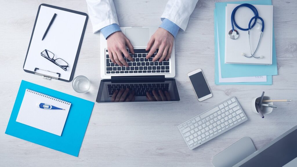 jovem em frente ao notebook com objetos que remetem a Medicina